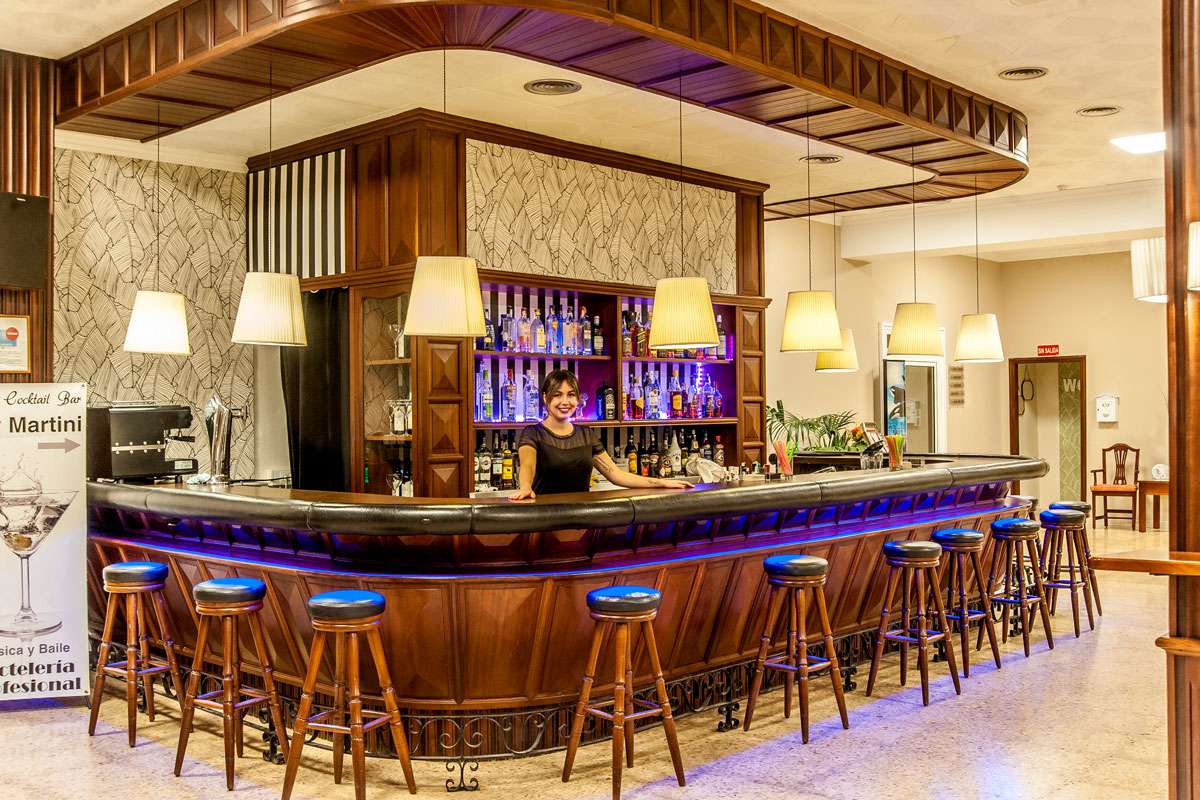 Serveuse souriante derrière le bar à cocktails éclairé dans un restaurant de Tenerife.