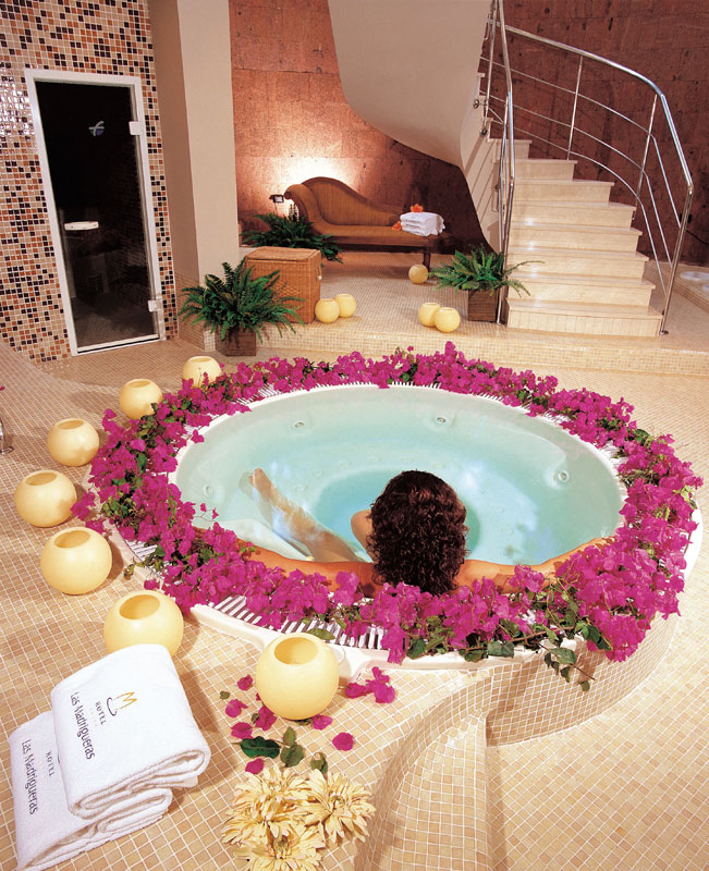 Personne se relaxant dans un spa entouré de fleurs roses à Tenerife.