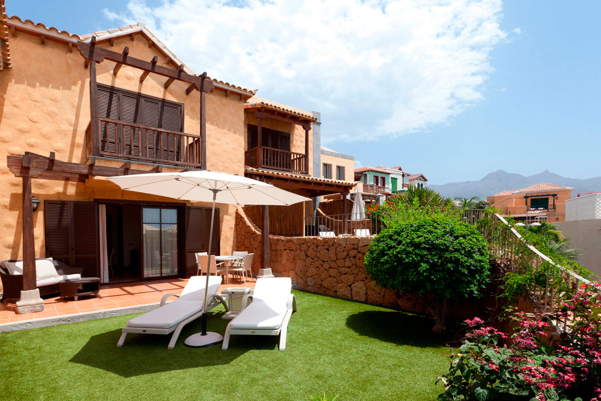 Maison en terrasse avec jardin et chaises longues à Tenerife, montagne en arrière-plan.