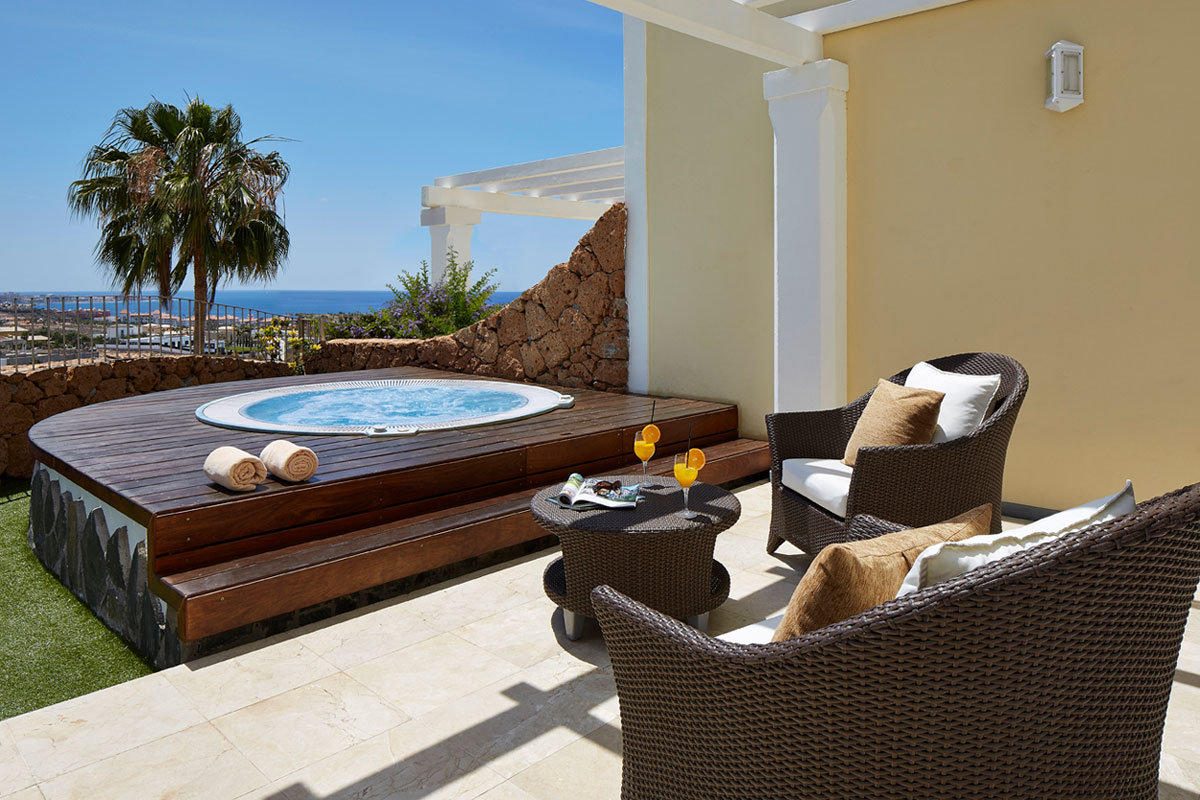 Jacuzzi extérieur avec vue sur l'océan à Tenerife, chaises et table avec verres.