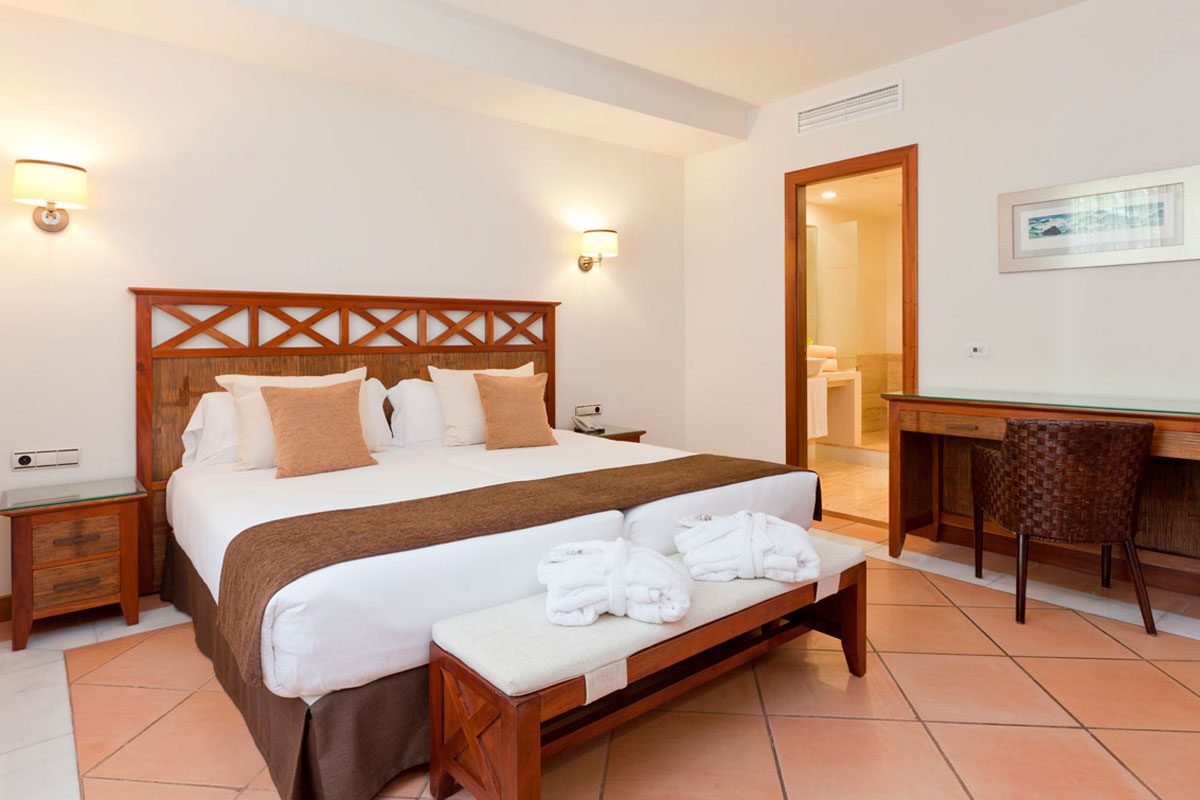 Chambre d'hôtel à Tenerife avec lit double, bureau et salle de bain adjacente.
