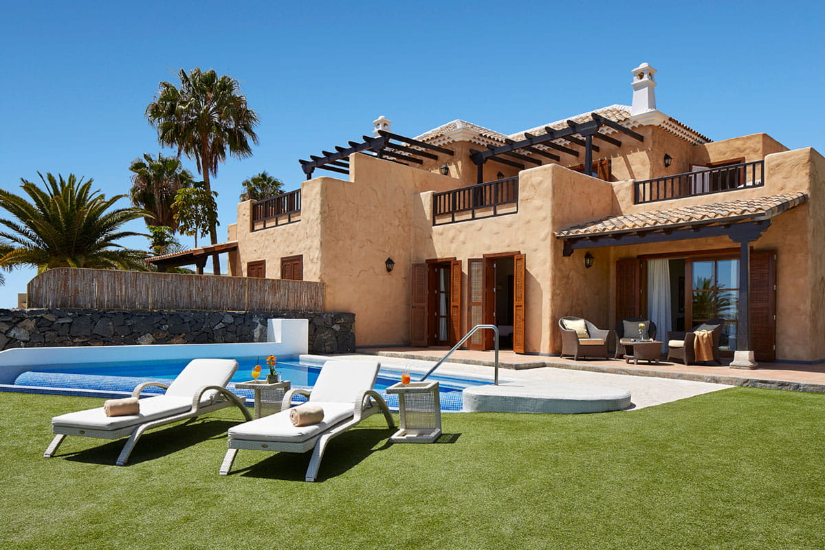 Deux chaises longues et piscine devant villa à Tenerife.