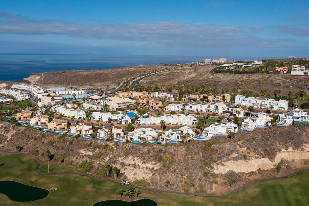 Vue aérienne de villas surplombant la mer à Tenerife avec terrain de golf à proximité.