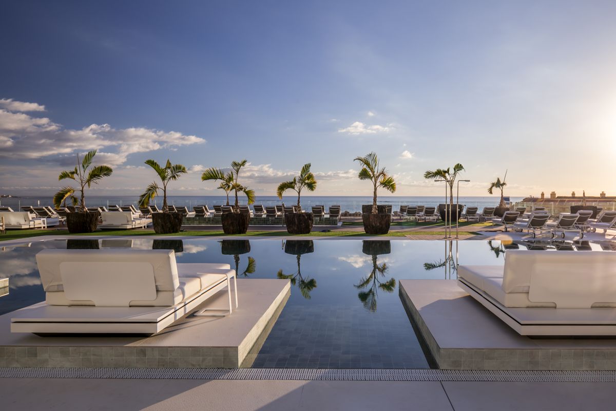 Transats blancs autour de la piscine avec vue sur l'océan à Costa Adeje, Tenerife.