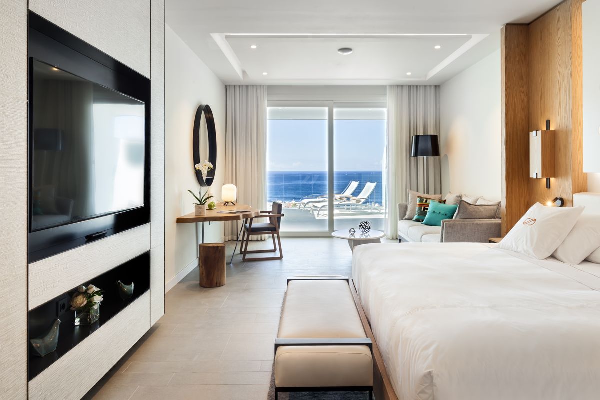 Chambre d'hôtel avec vue mer à Tenerife, canapé et bureau près de la fenêtre.