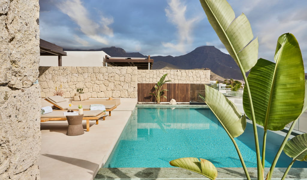 Piscine avec chaises longues à Tenerife, vue sur montagnes.