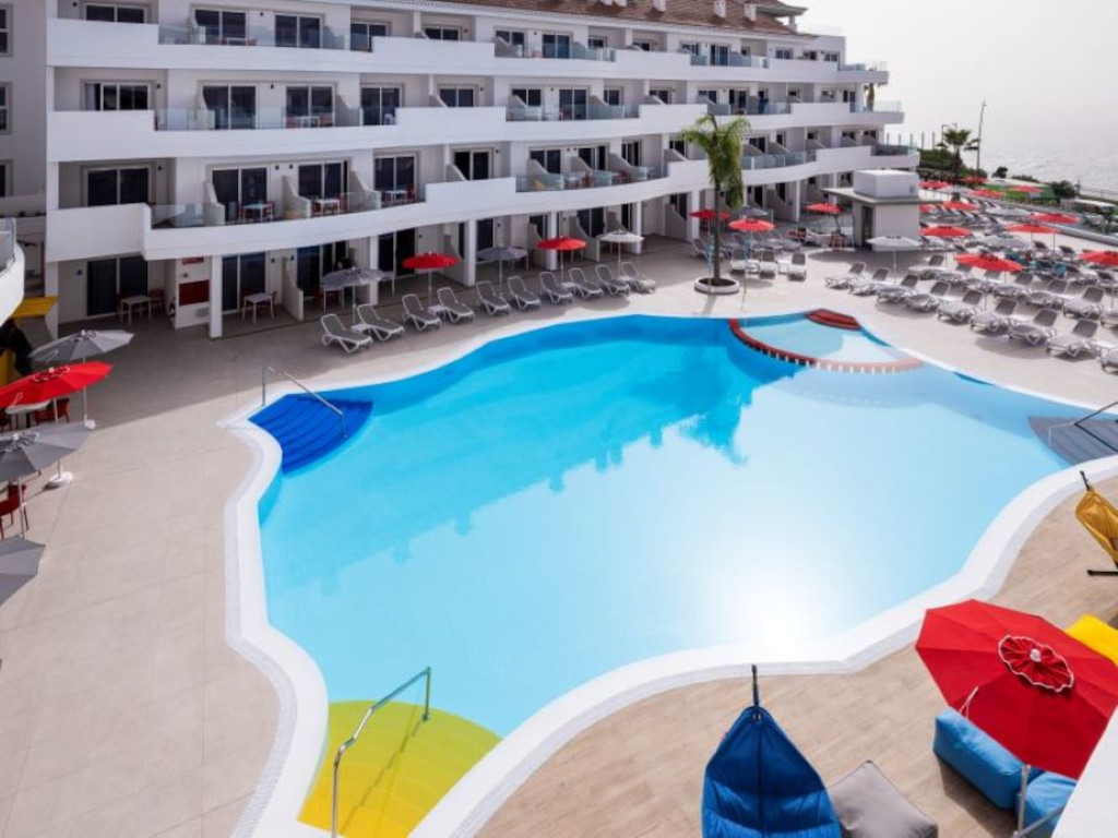 Piscine entourée de chaises longues et de parasols dans un complexe touristique à Tenerife.