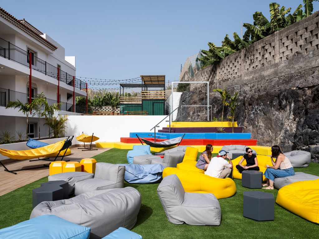 Les gens discutent en plein air avec des hamacs et des poufs colorés à Tenerife.