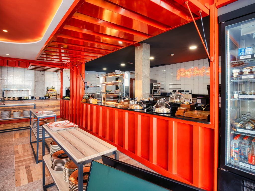 Intérieur d’un restaurant à Tenerife avec des tables en bois et un comptoir rouge.