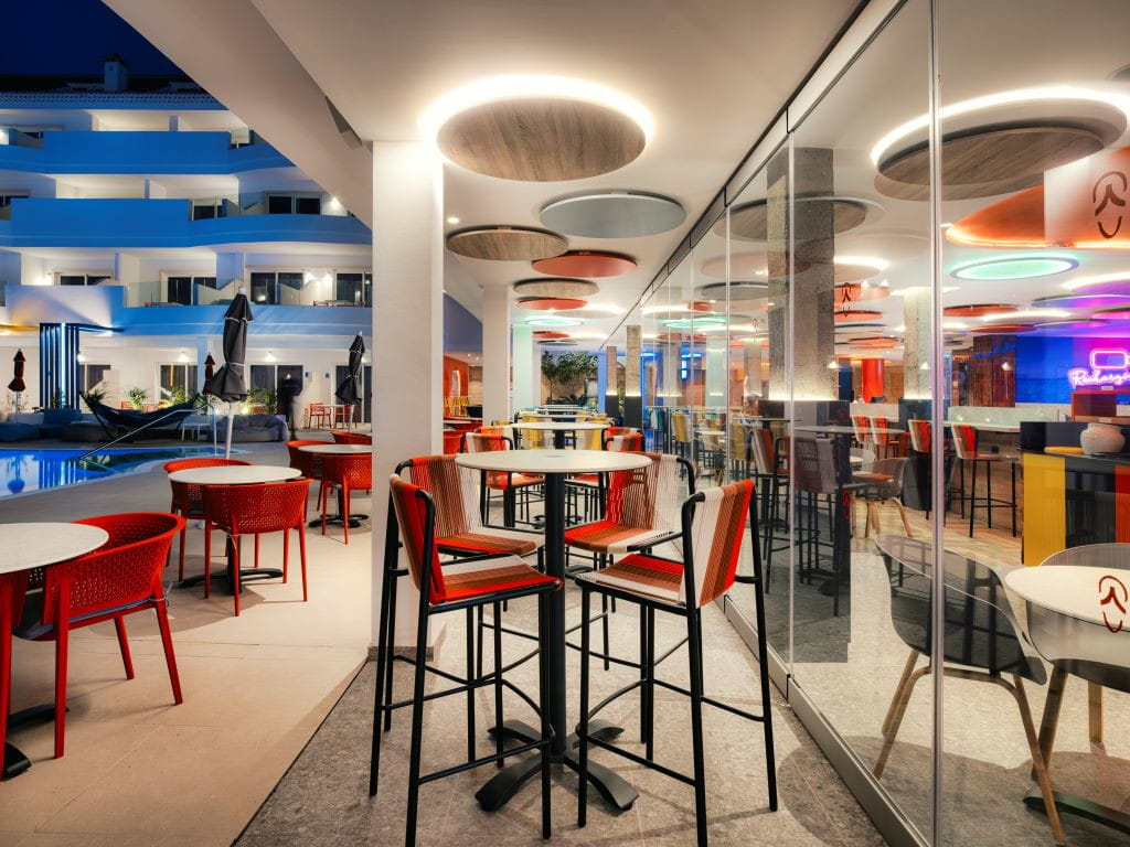 Terrasse d’un restaurant avec des tables et chaises rouges dans un hôtel à Tenerife la nuit.