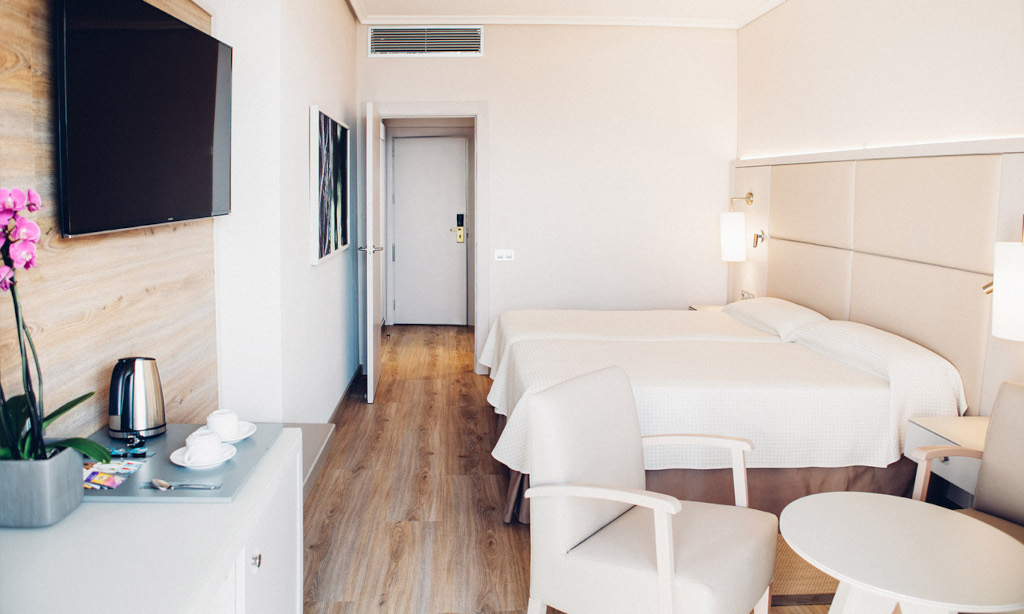 Chambre d'hôtel lumineuse avec lits jumeaux et télévision à Tenerife.