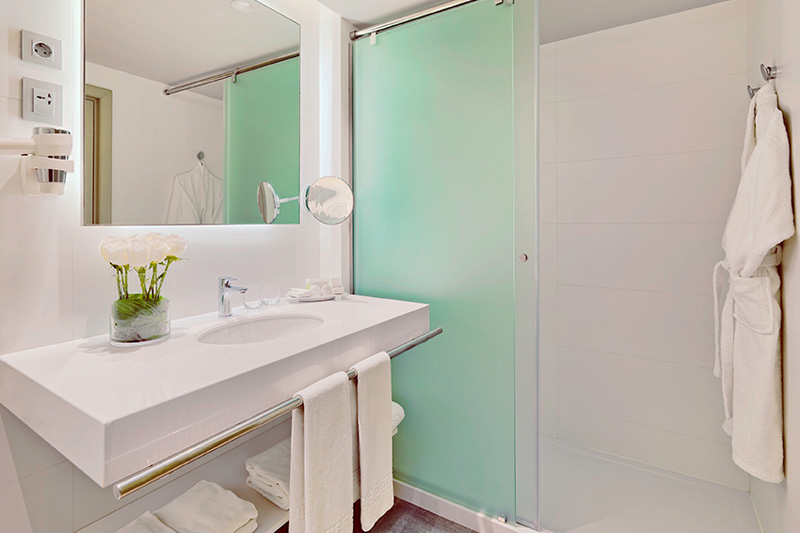 Salle de bain moderne avec lavabo, serviettes blanches et douche à Puerto de la Cruz.