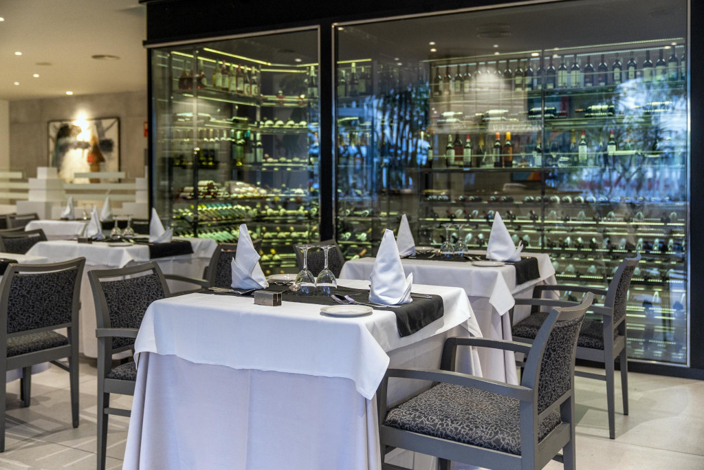 Tables dressées dans un restaurant à Tenerife, avec une cave à vin en arrière-plan.