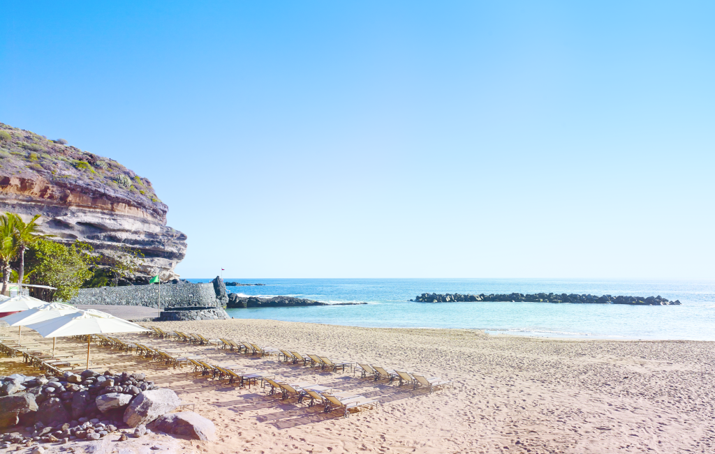 Plage de sable doré avec parasols et rochers à Playa del Duque, Tenerife.