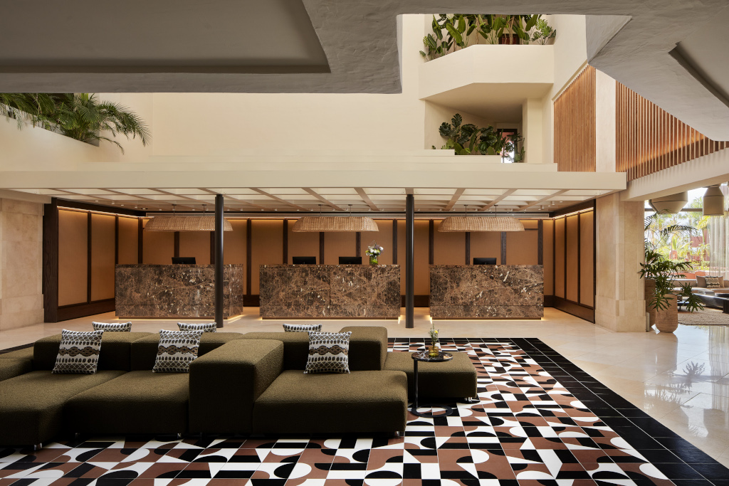 Hall d'accueil d'un hôtel moderne à Tenerife avec réception en marbre et canapé géométrique.