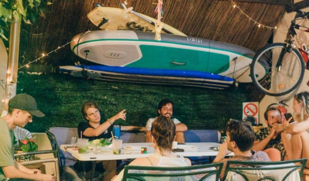Personnes assises autour d'une table à Tenerife avec un paddle et un vélo accrochés au mur.