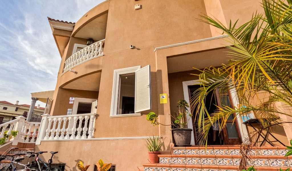 Maison beige avec balcons et plantes à Adeje, Tenerife.