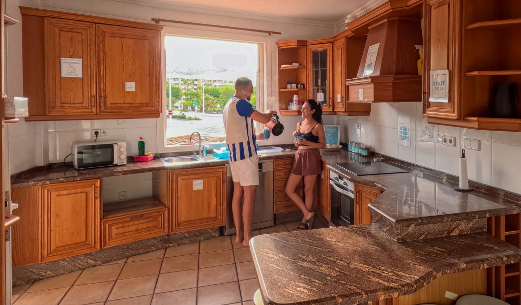 Un couple prépare du café dans une cuisine avec vue sur un parc à Tenerife.