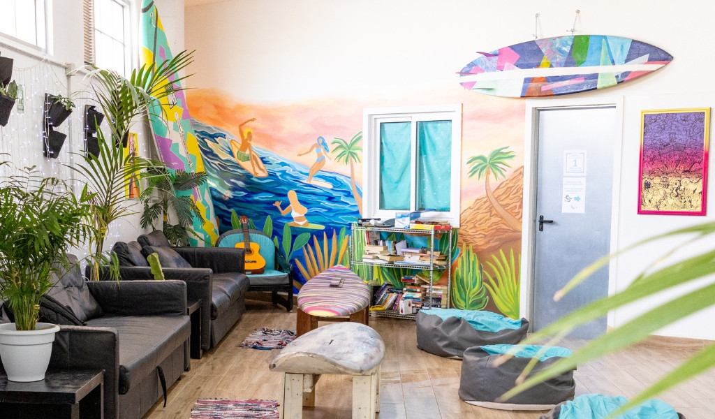 Un salon avec canapé, guitare et tableau coloré de surfeurs à Tenerife.