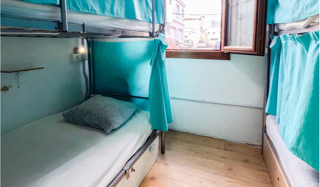 Lit superposé avec rideaux bleus et oreiller dans une chambre à Tenerife.