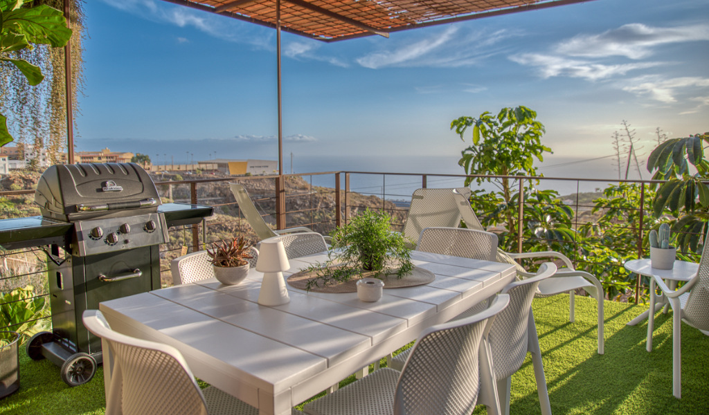 Terrasse avec table blanche, plantes et barbecue vue océan à Tenerife.