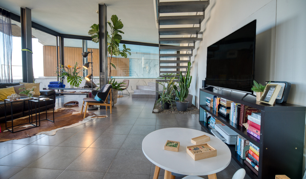 Salon moderne avec escalier, plantes et télévision à Tenerife.