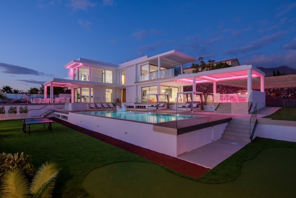 Maison moderne avec piscine à Costa Adeje, Tenerife, éclairée en rose au crépuscule.