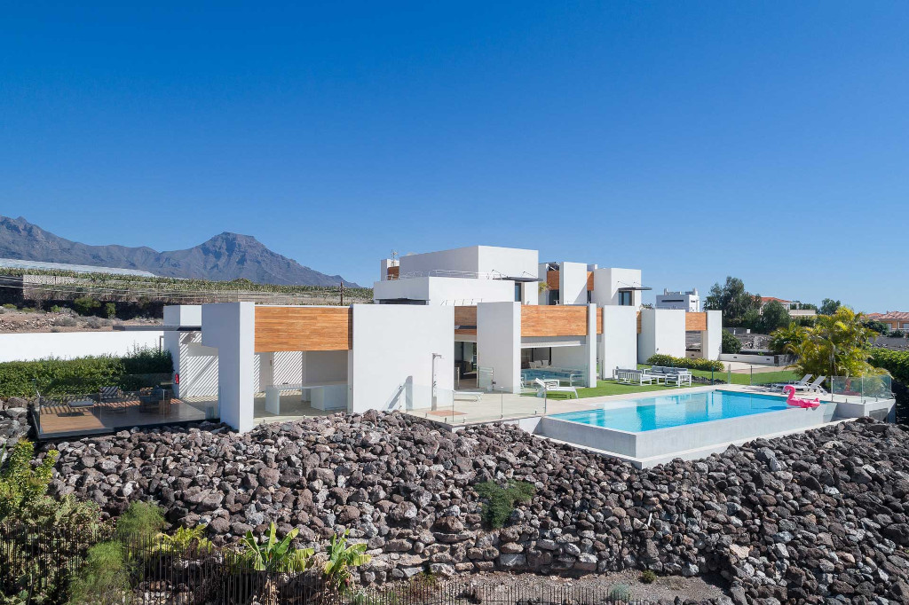 Maison moderne avec piscine à Tenerife, montagnes en arrière-plan.