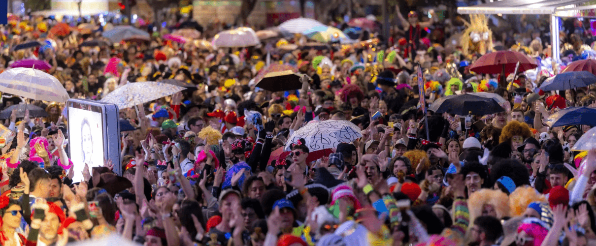 Foule en fête avec parapluies et costumes colorés au carnaval de Santa Cruz de Tenerife.