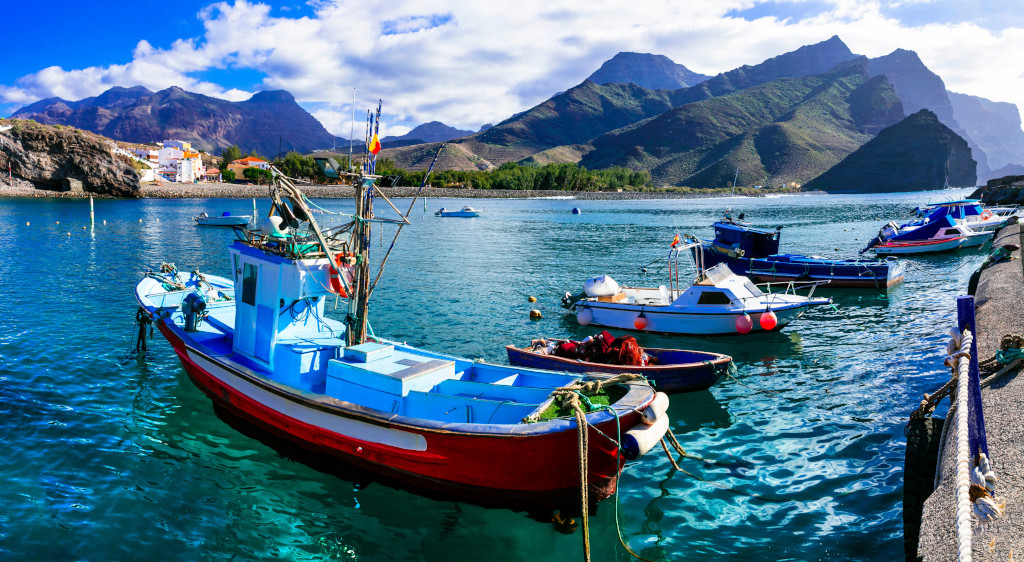 Bateaux colorés dans le port de Garachico à Tenerife devant des montagnes.