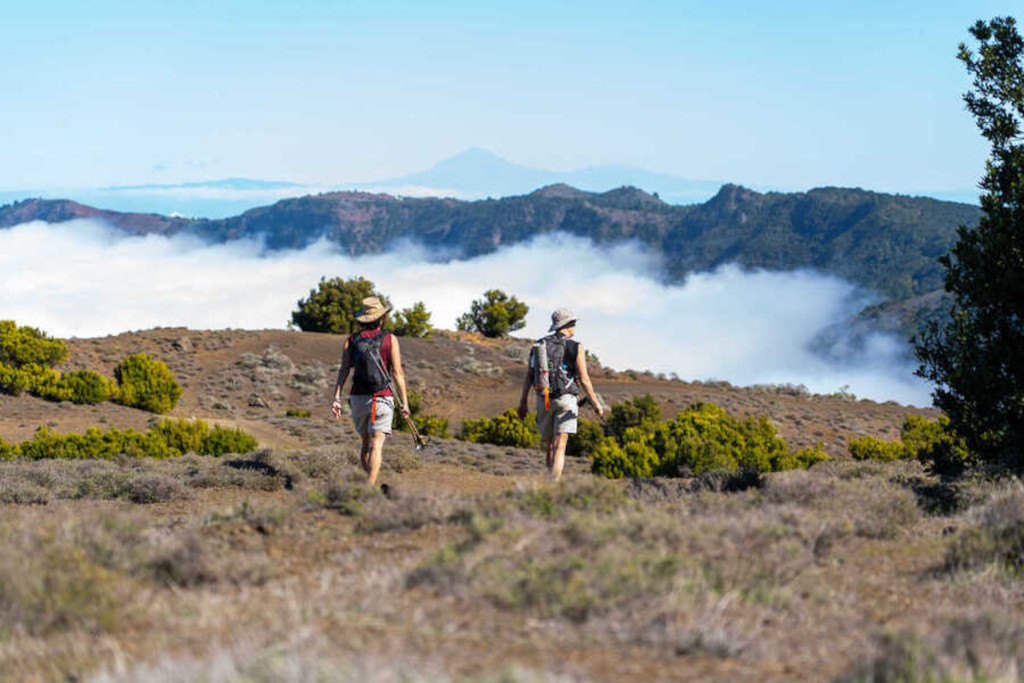 Randonneurs sur un sentier montagneux à Tenerife avec nuages en arrière-plan.