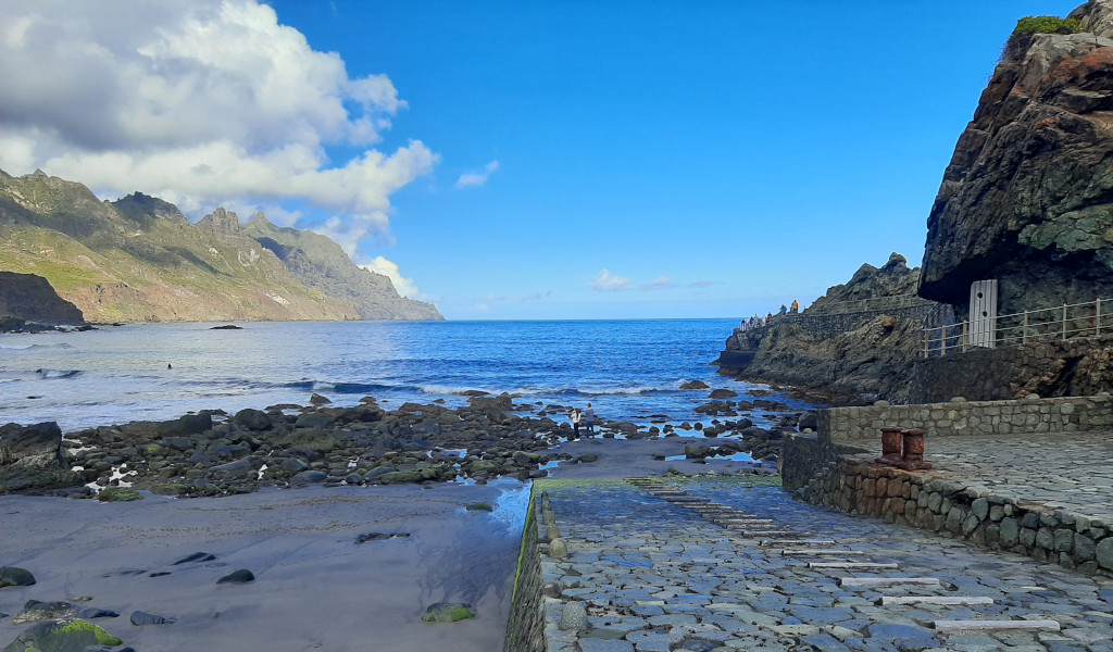 Plage rocheuse et montagnes à Almaciga, Tenerife, avec ciel bleu et nuages.