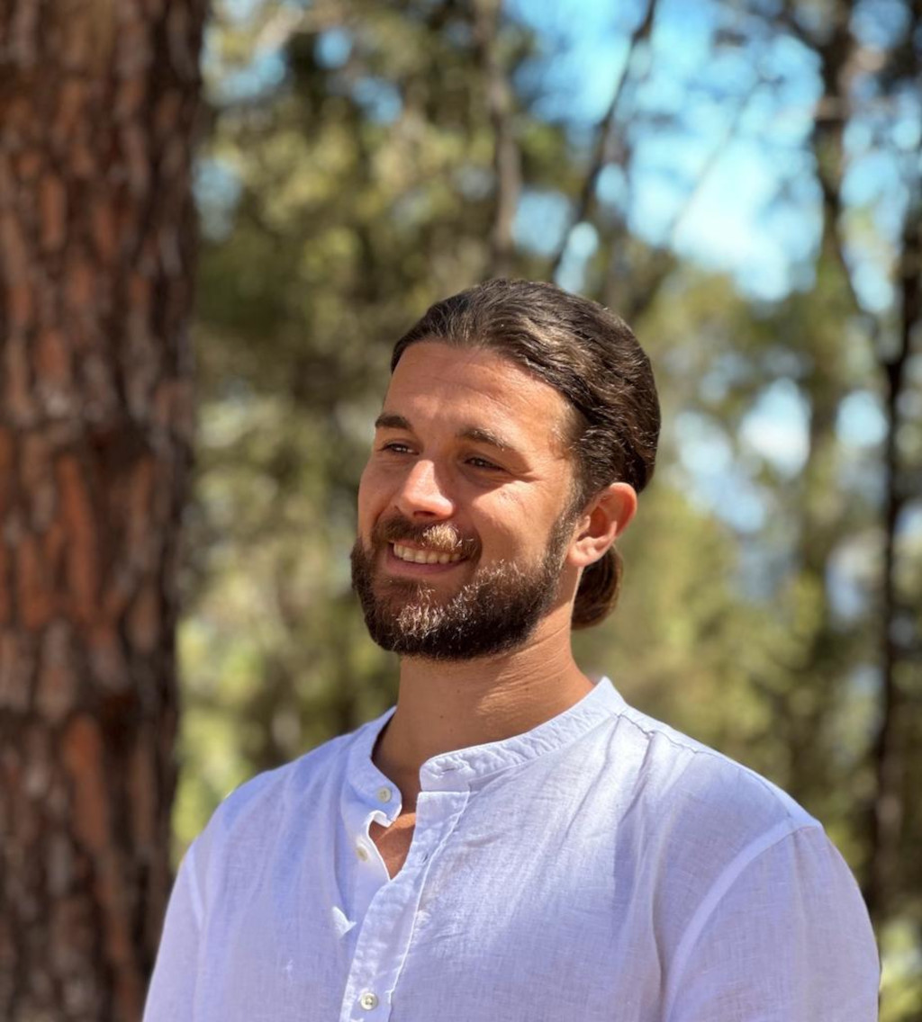 Une personne souriante en chemise blanche devant des arbres à Tenerife.
