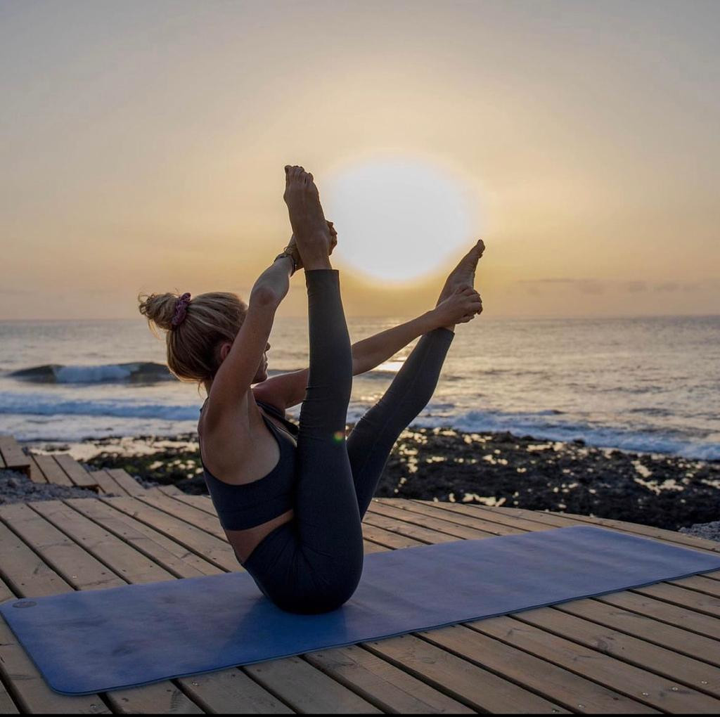 Personne faisant du yoga au coucher du soleil sur une terrasse à Tenerife.