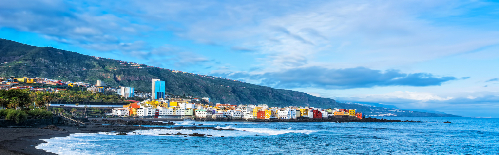 Vue côtière colorée de Puerto de la Cruz, Tenerife, avec montagnes en arrière-plan.