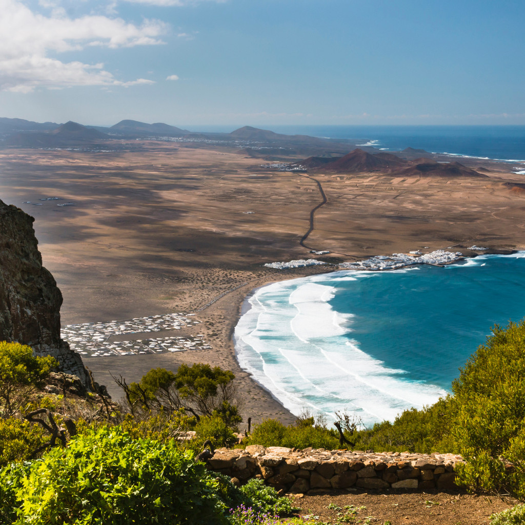 Baie avec plage de sable et mer bleue à Tenerife sous ciel dégagé.