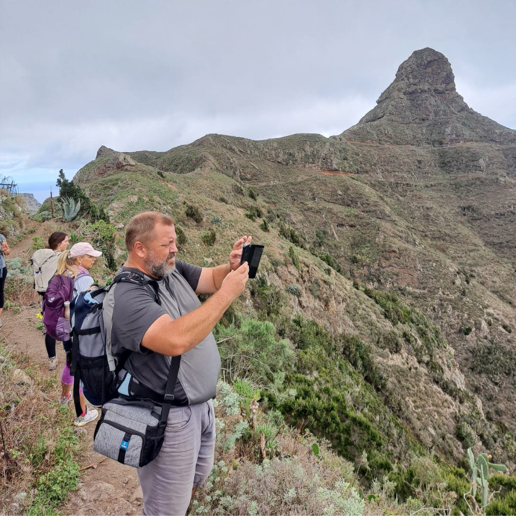 Des personnes marchent sur un sentier à Tenerife, avec des montagnes en arrière-plan.