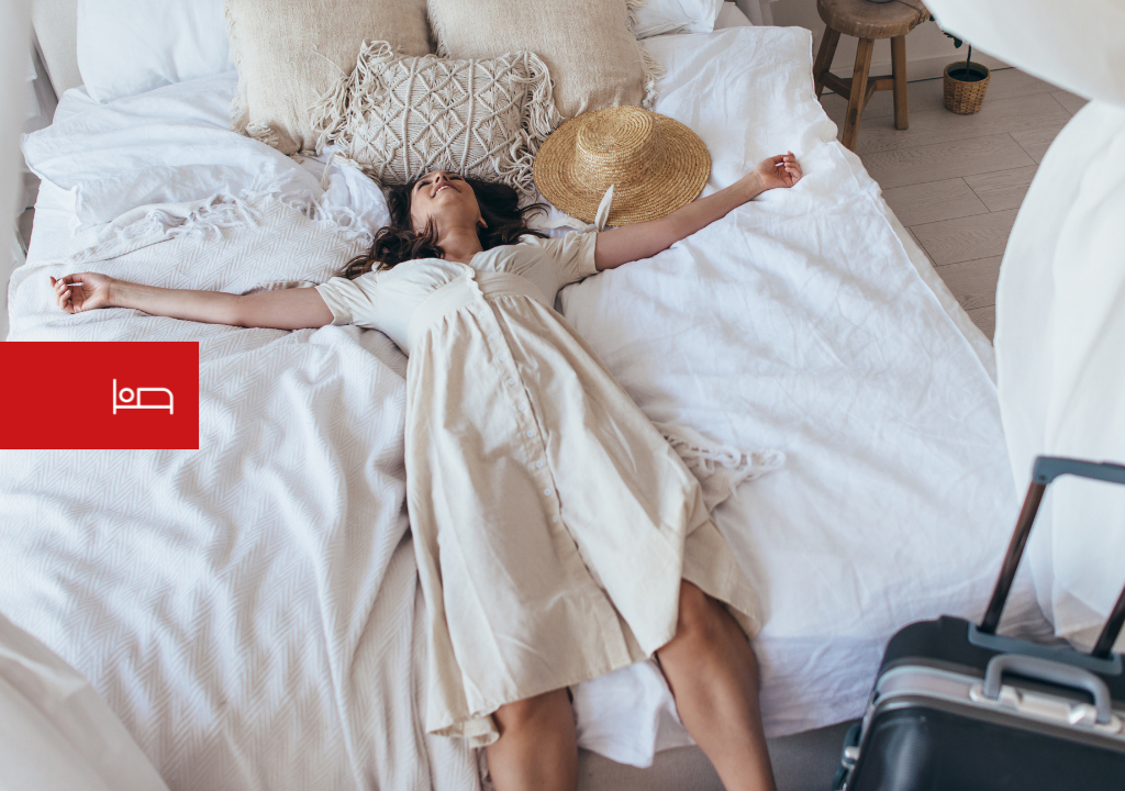 Personne se reposant sur un lit à côté d'une valise et d'un chapeau à Tenerife.
