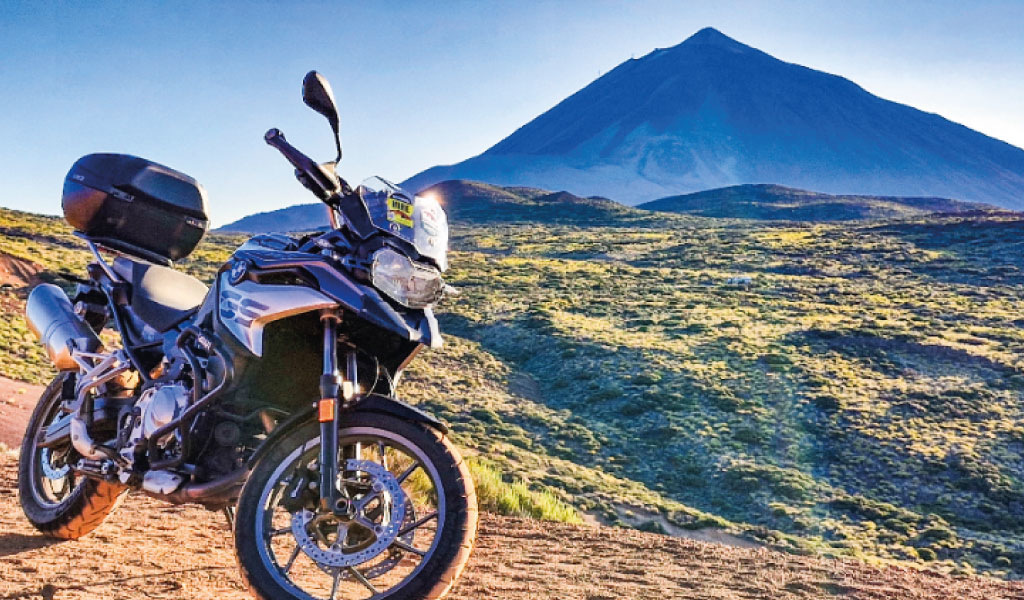Moto garée devant le mont Teide à Tenerife sous un ciel bleu.