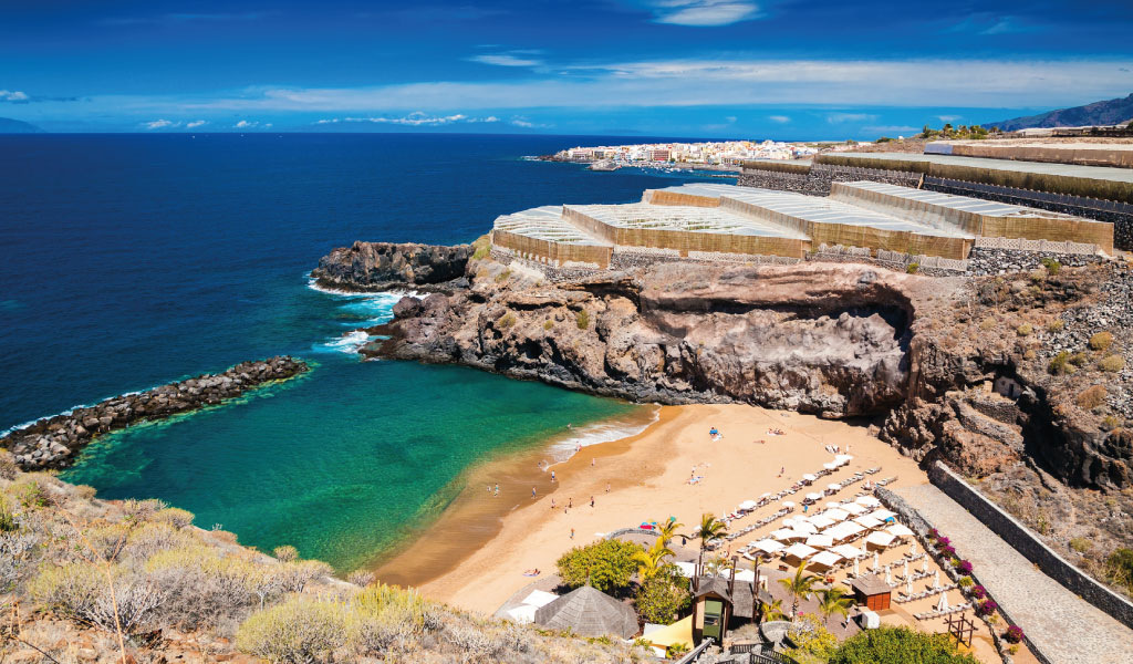 Plage avec parasols et mer bleue à Puerto de Santiago, Tenerife.