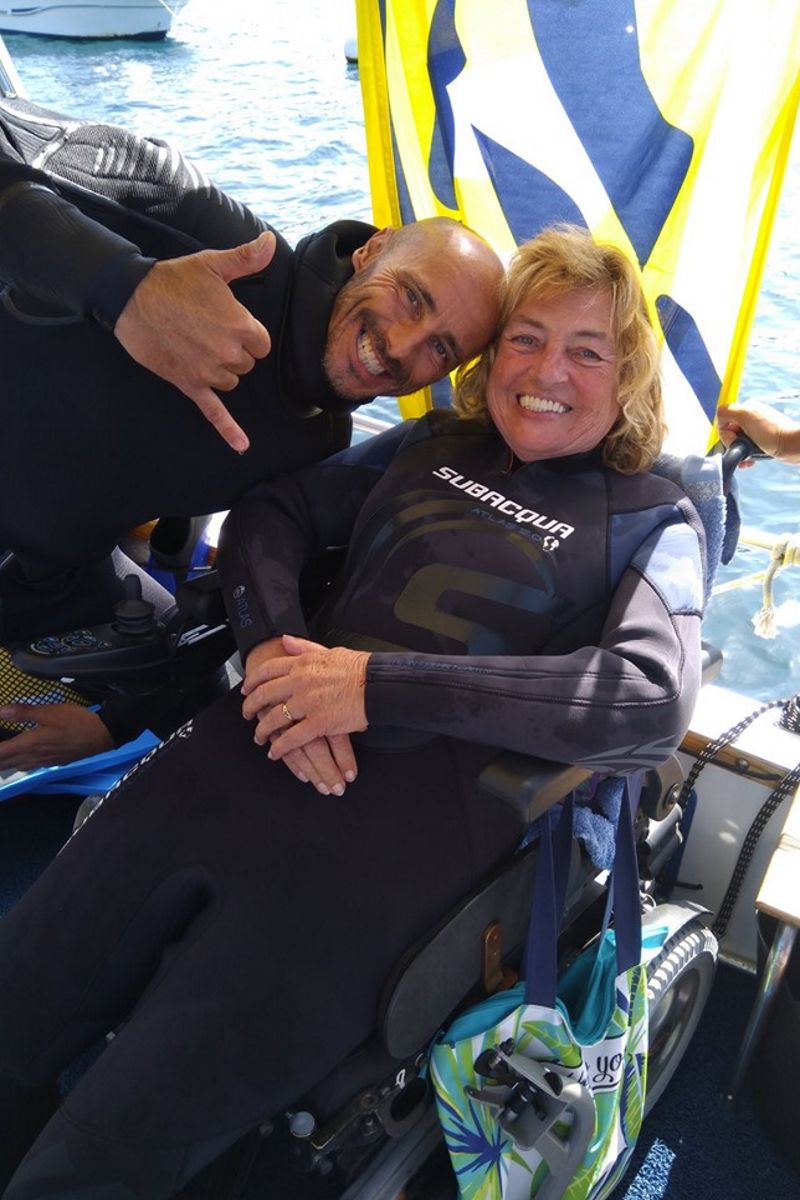 Des gens en combinaisons de plongée souriantes en fauteuil roulant près de la mer à Tenerife.