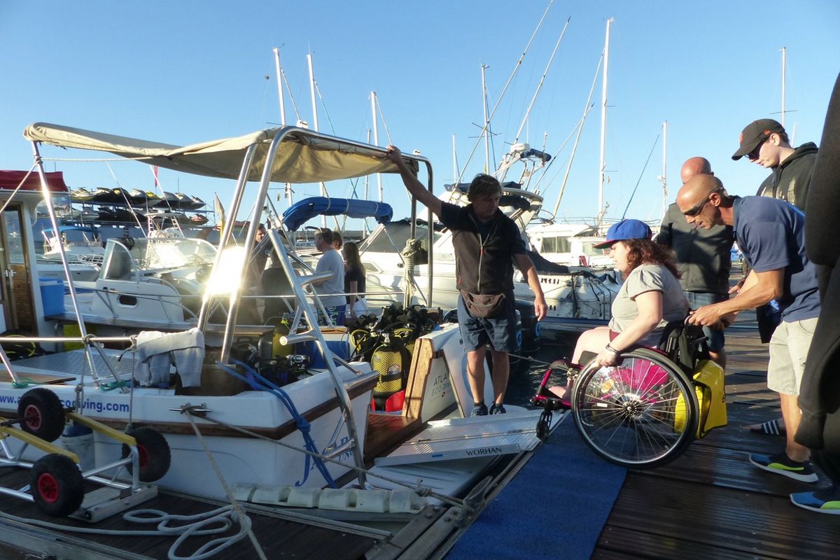 Personne en fauteuil roulant montant à bord d’un bateau à Tenerife avec l’aide de plusieurs personnes.