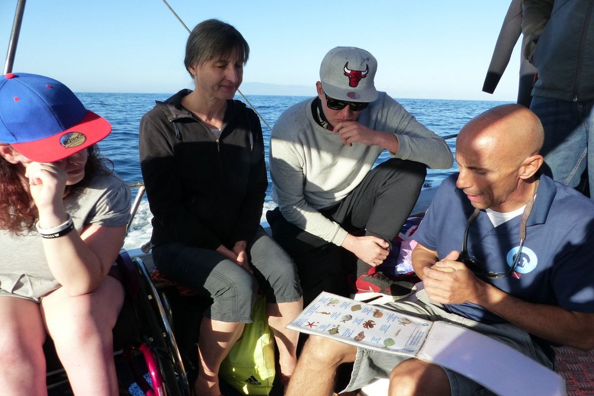 Les personnes à bord d’un bateau à Tenerife consultent une liste avec des images et du texte pendant qu’elles naviguent.