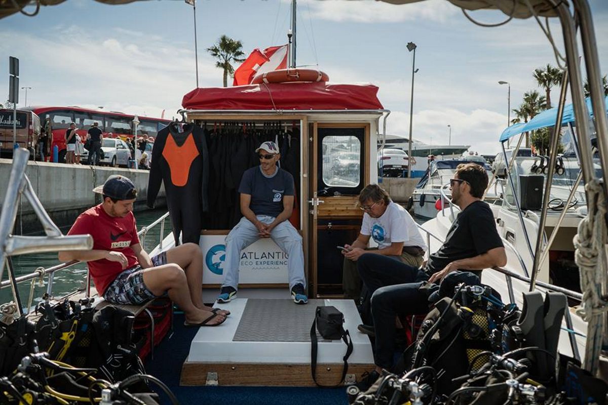 Des gens assis sur un bateau de plongée à Puerto Colón, Tenerife, en combinaison de plongée.