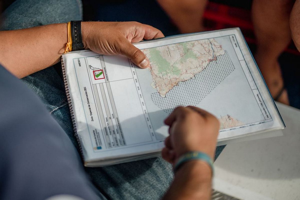 Personne tenant une carte de Tenerife dans un carnet spiralé.
