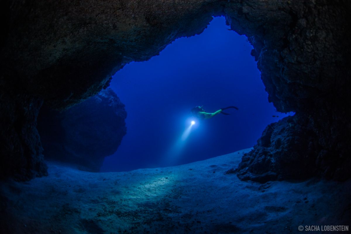 Plongeur souterrain illuminant le fond océanique à Tenerife.