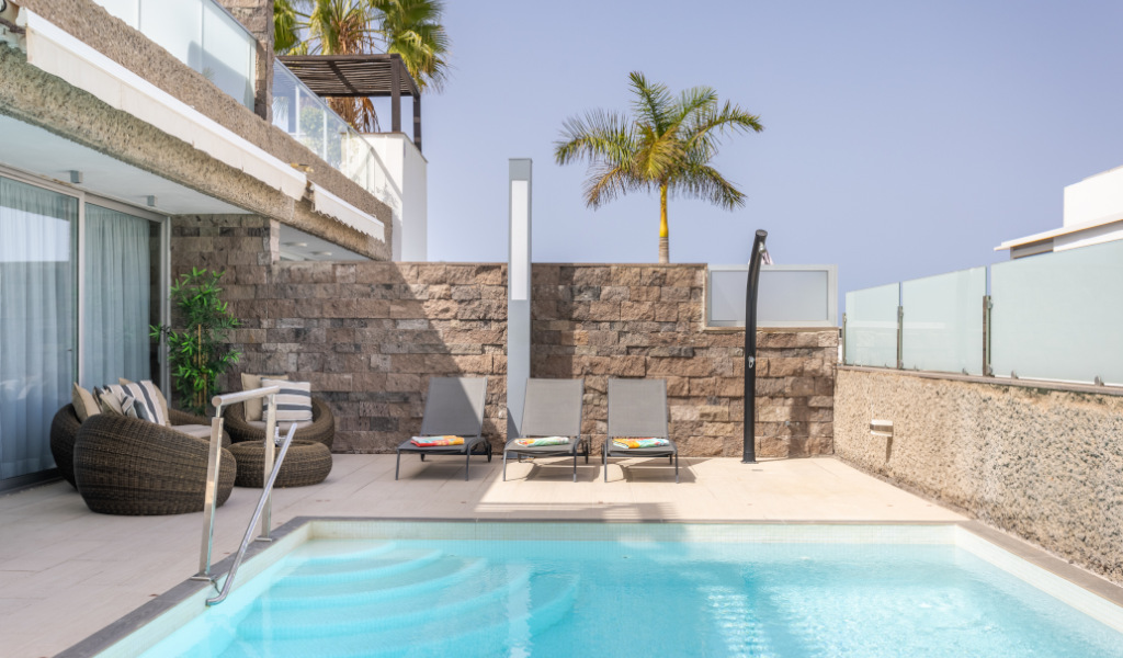 Piscine extérieure avec chaises et palmier dans un hôtel à Tenerife.