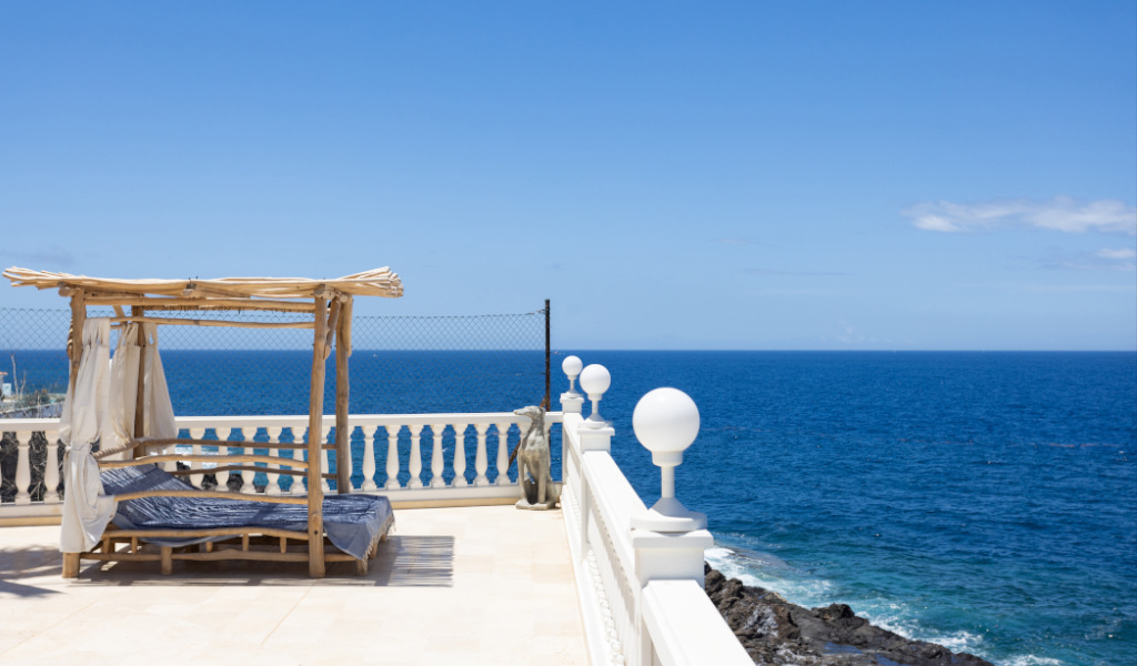 Chaise longue en bois face à la mer à Tenerife avec un ciel dégagé.