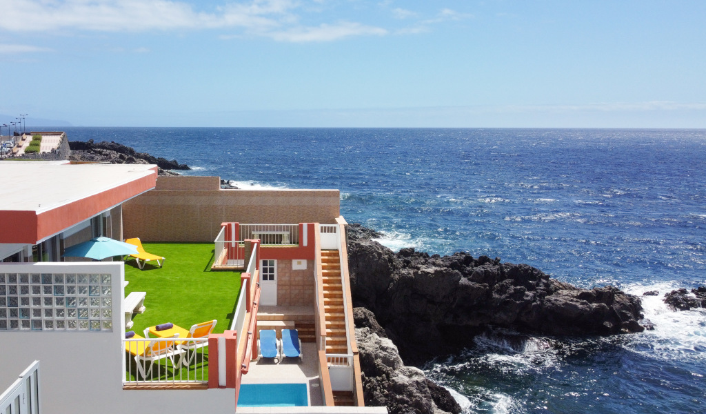 Terrasse avec pelouse et chaises longues au bord de la mer sur une falaise à Tenerife.