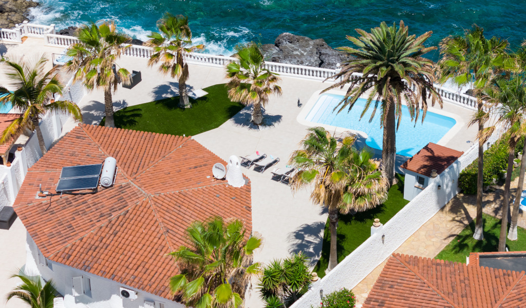 Vue aérienne de la terrasse avec piscine, palmiers et mer à Tenerife.